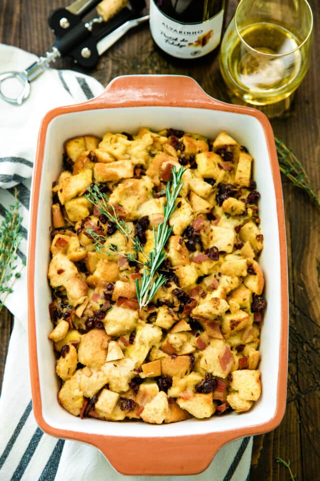 overhead photo of Easy Bacon Apple Stuffing Recipe in a casserole dish served with wine