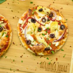 overhead photo of Easy Greek Pita Pizzas Recipe on a wooden cutting board