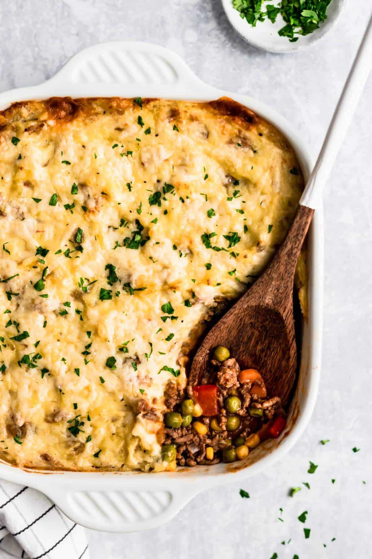 Shepherd's Pie being served out of dish with a large wooden spoon.