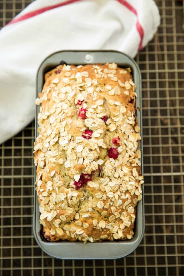 baked cranberry bread in a loaf pan on a cooling rack