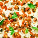 Bruschetta Chicken Alfredo Flatbread topped with fresh basil leaves