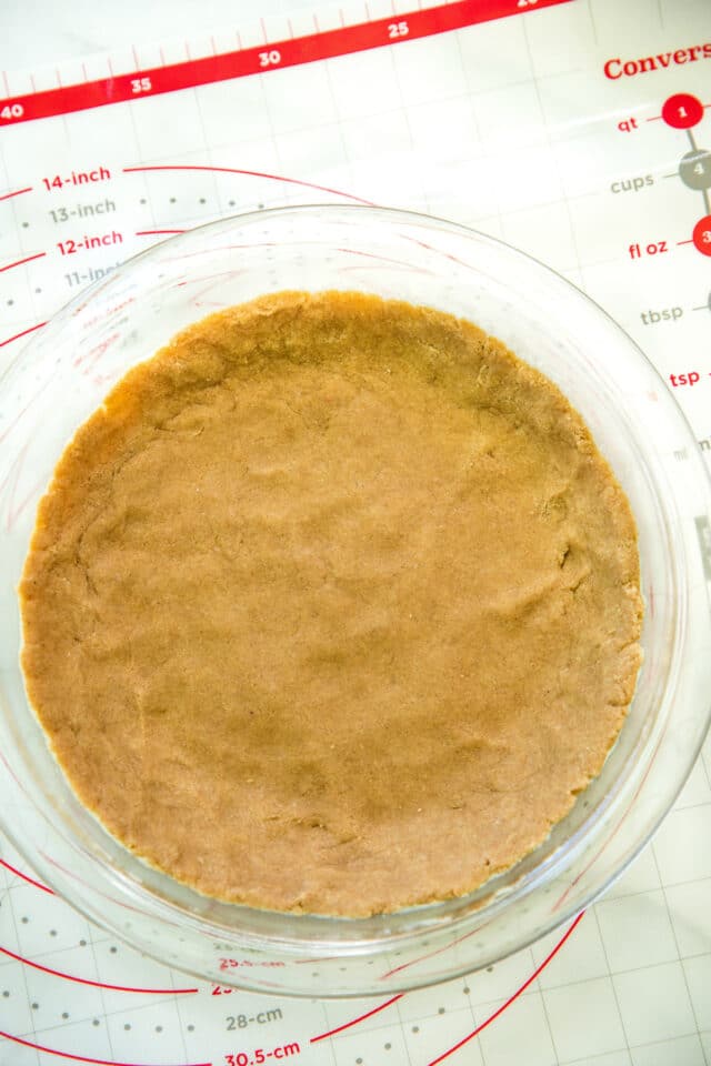 a pressed down pie crust in a pie plate before baking
