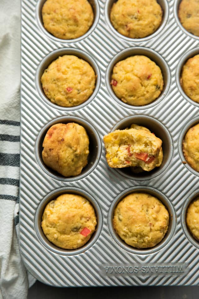 cooked cornbread muffins in a muffin pan on a striped handtowel