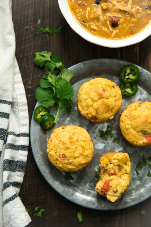 Mexican cornbread muffins served on a silver plate with a bowl of soup on the side