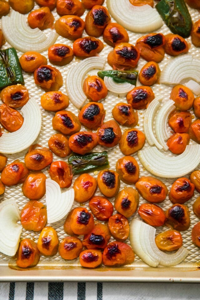 roasted tomatoes, onions and jalapeños on a baking sheet