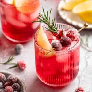 Cranberry mocktail topped with a lemon slice, sugared cranberries and a sprig of rosemary.