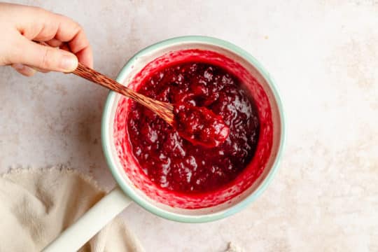 using a wooden spoon to serve cranberry sauce