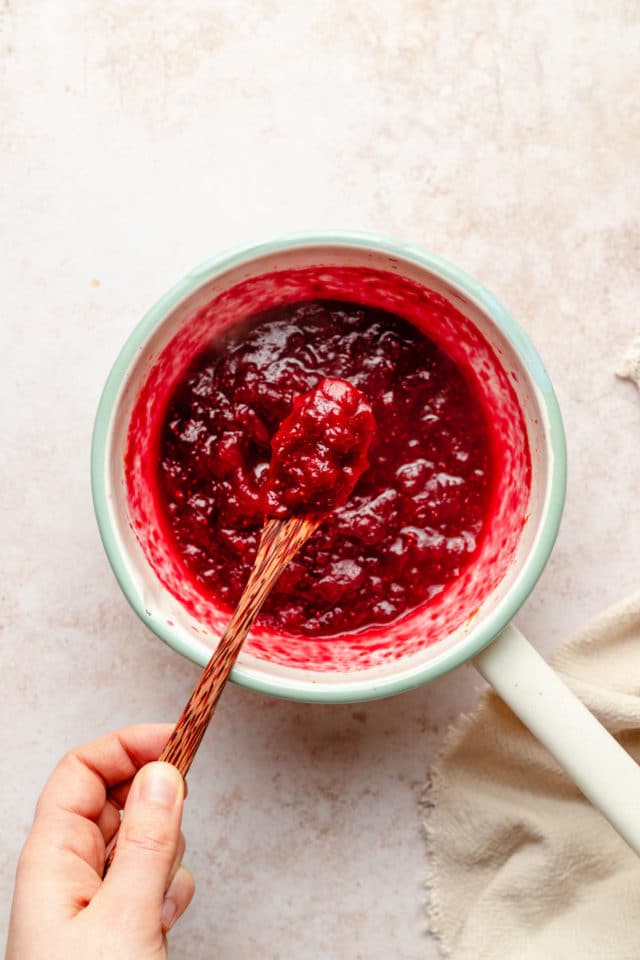 using a wooden spoon to serve cranberry sauce
