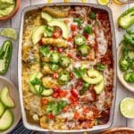 Chicken enchilada recipe in a glass baking dish topped with sliced jalapeños and avocado slices.