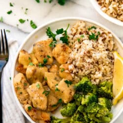 chicken with gravy served with brown rice and broccoli on a white plate