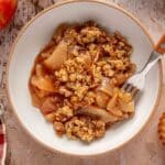 Apple crisp served in a bowl with a fork.