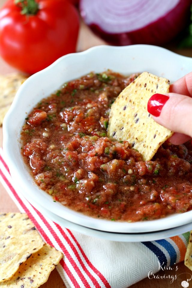 woman's hand dipping a chip into a bowl full of salsa