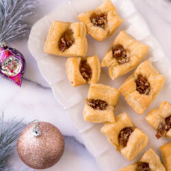Puff Pastry Brie Bites served on a white serving tray near Christmas ornaments