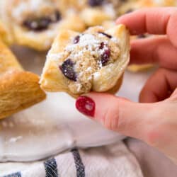 woman's hand holding a grape almond puff pastry bite