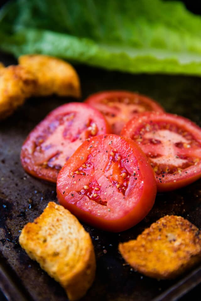 tomato slices with freshly cracked pepper on a baking sheet
