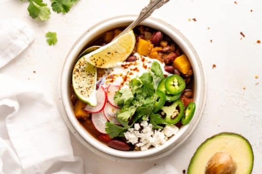 butternut squash chili garnished with radishes, jalapeños and cheese
