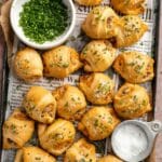 Breakfast crescent rolls on a baking pan with a bowl of chives and flaky salt.
