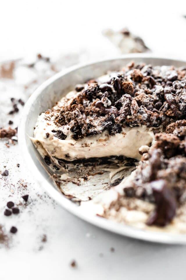 no bake dirt pie in a white pie dish with a slice cut out