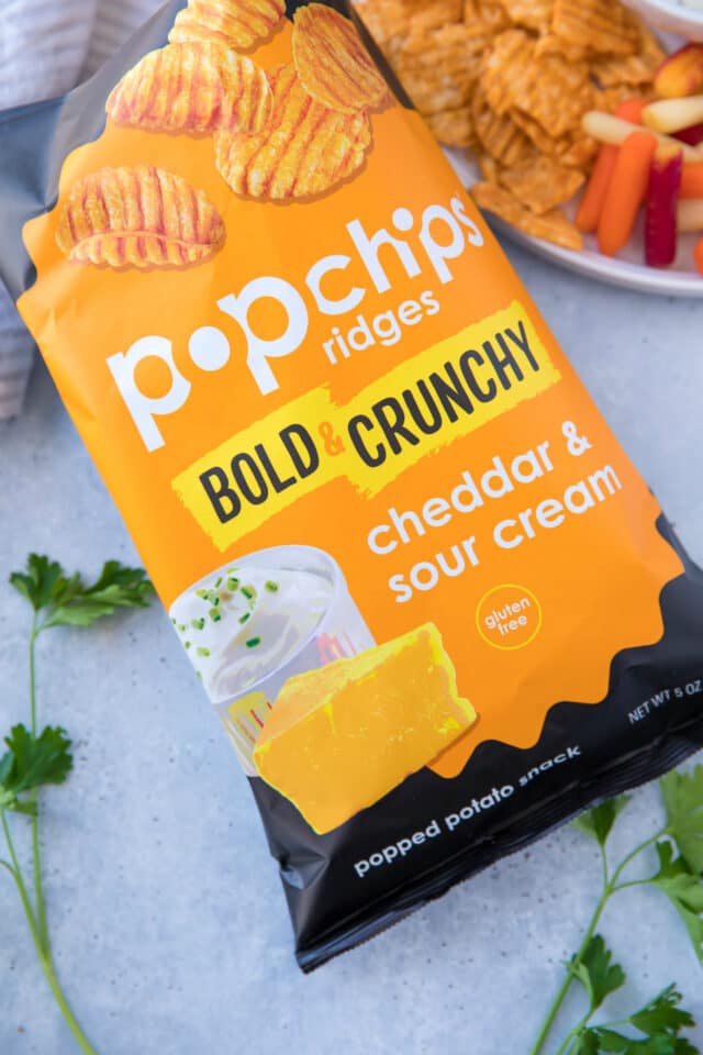 bag of cheddar & sour cream Popchips on a counter near a serving platter