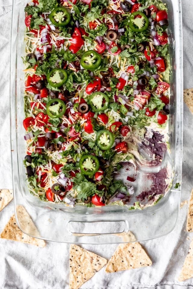 7-layer dip in a large glass dish served with tortilla chips