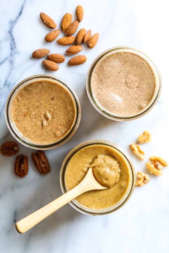 three jars of nut butter surrounded by almonds 