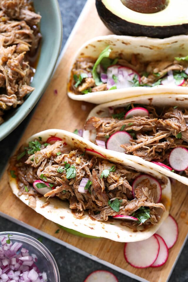 carnitas soft tacos on a wooden cutting board