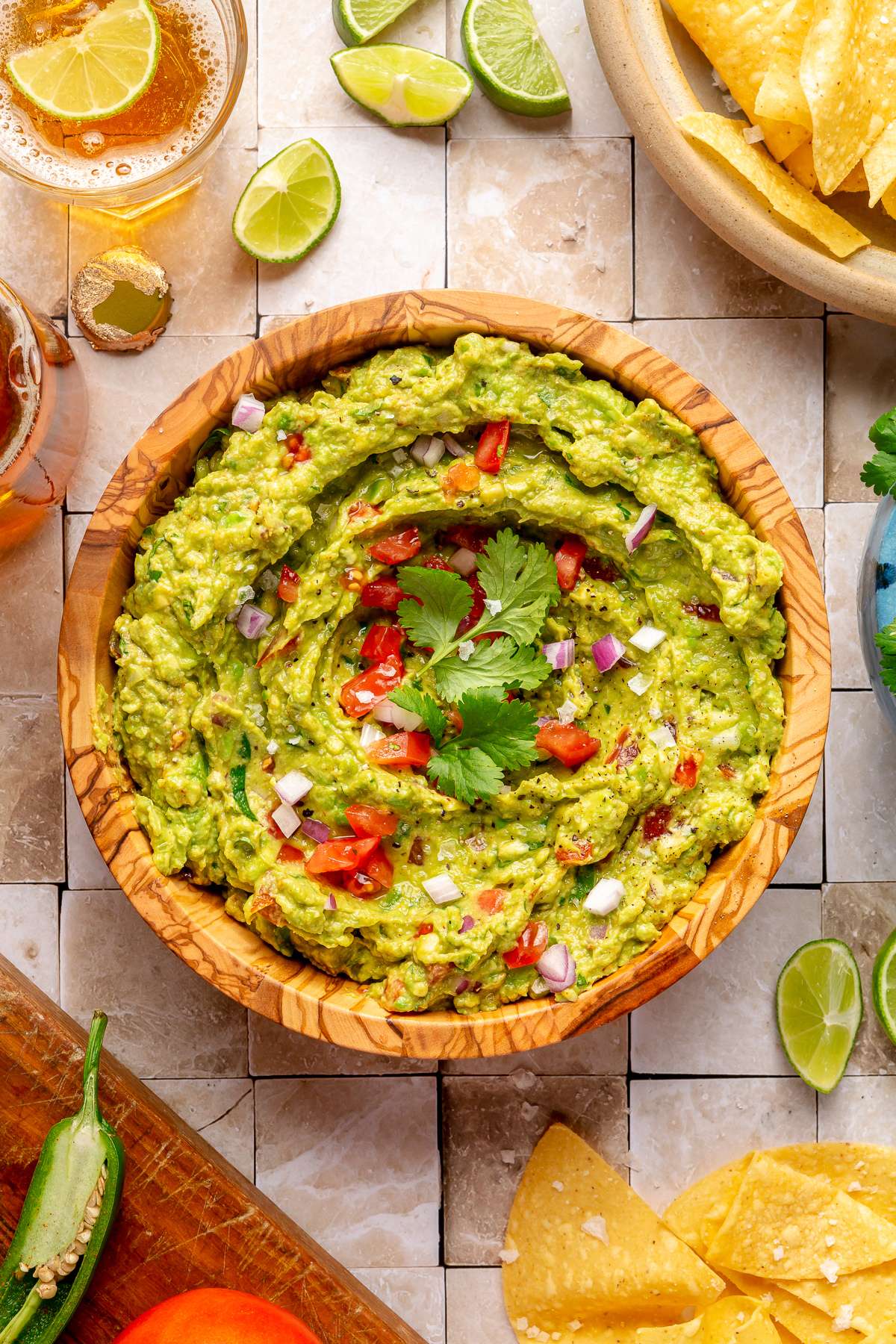 Bowl of guacamole garnished with fresh cilantro, diced tomato and onion.