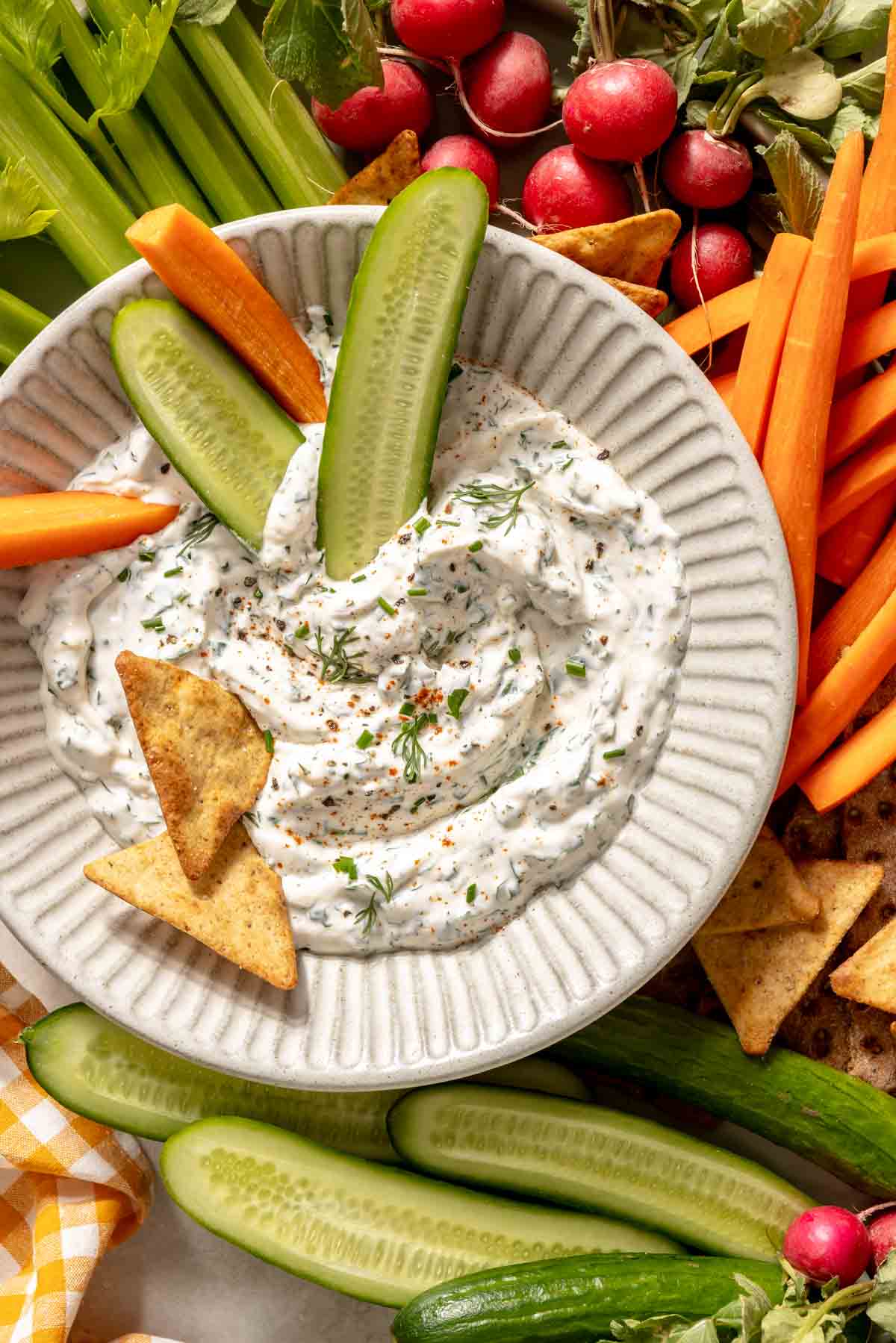 Ranch dip in a bowl with cucumbers, carrots and crackers.