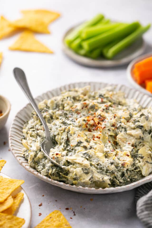 Crockpot spinach artichoke dip in a plate with a spoon.