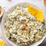 Spinach artichoke dip served in a small bowl with chips.