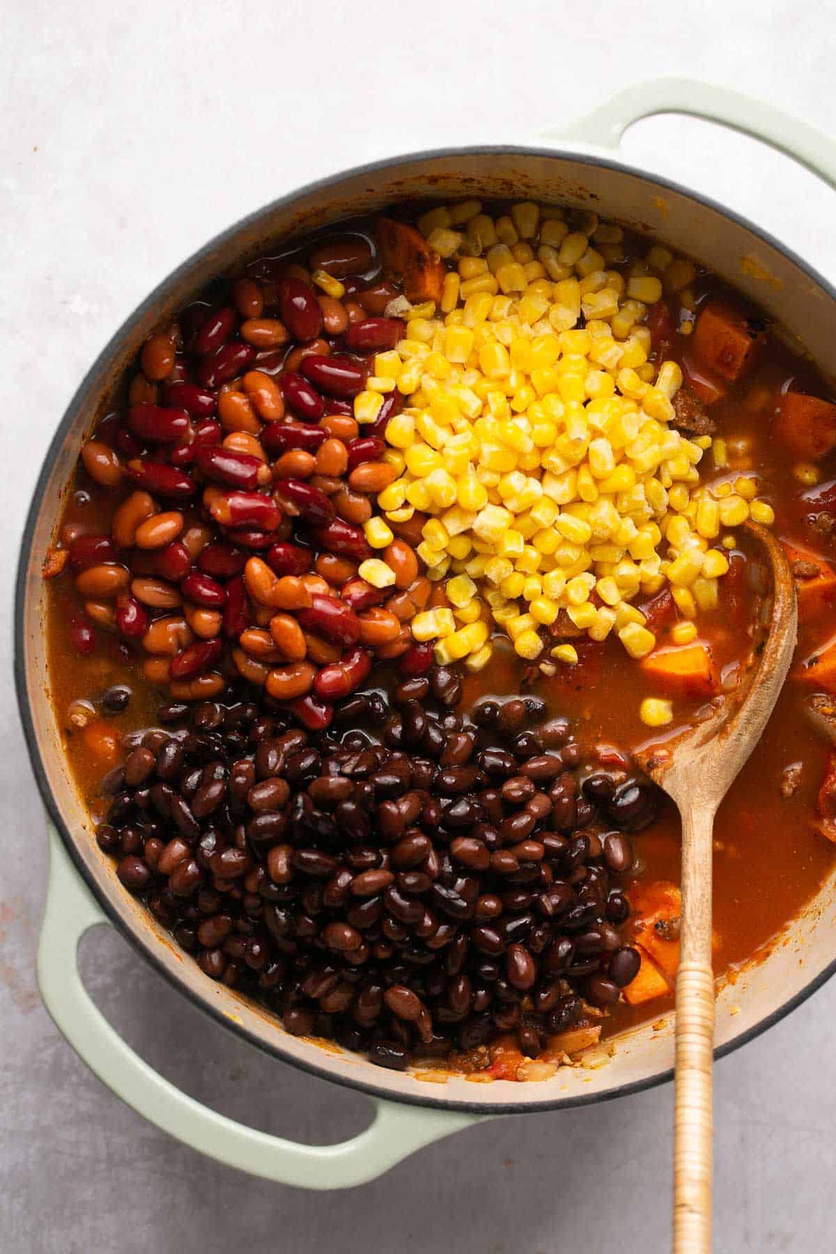 Adding corn and beans to a large pot.