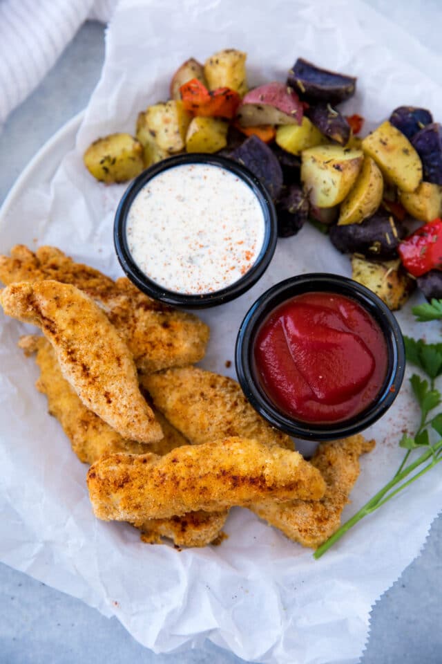 plate filled with chicken tenders, veggies and dipping sauces 
