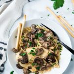 white bowl filled with Chicken Marsala and pasta with a black fork