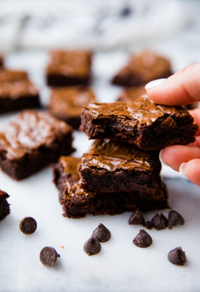 woman's hand taking a brownie off the top of a stack of brownies