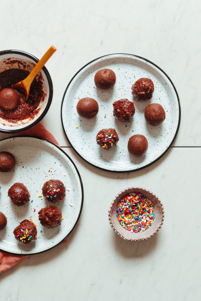 Chocolate Cake Bites on white plates with a bowl full of colorful sprinkles