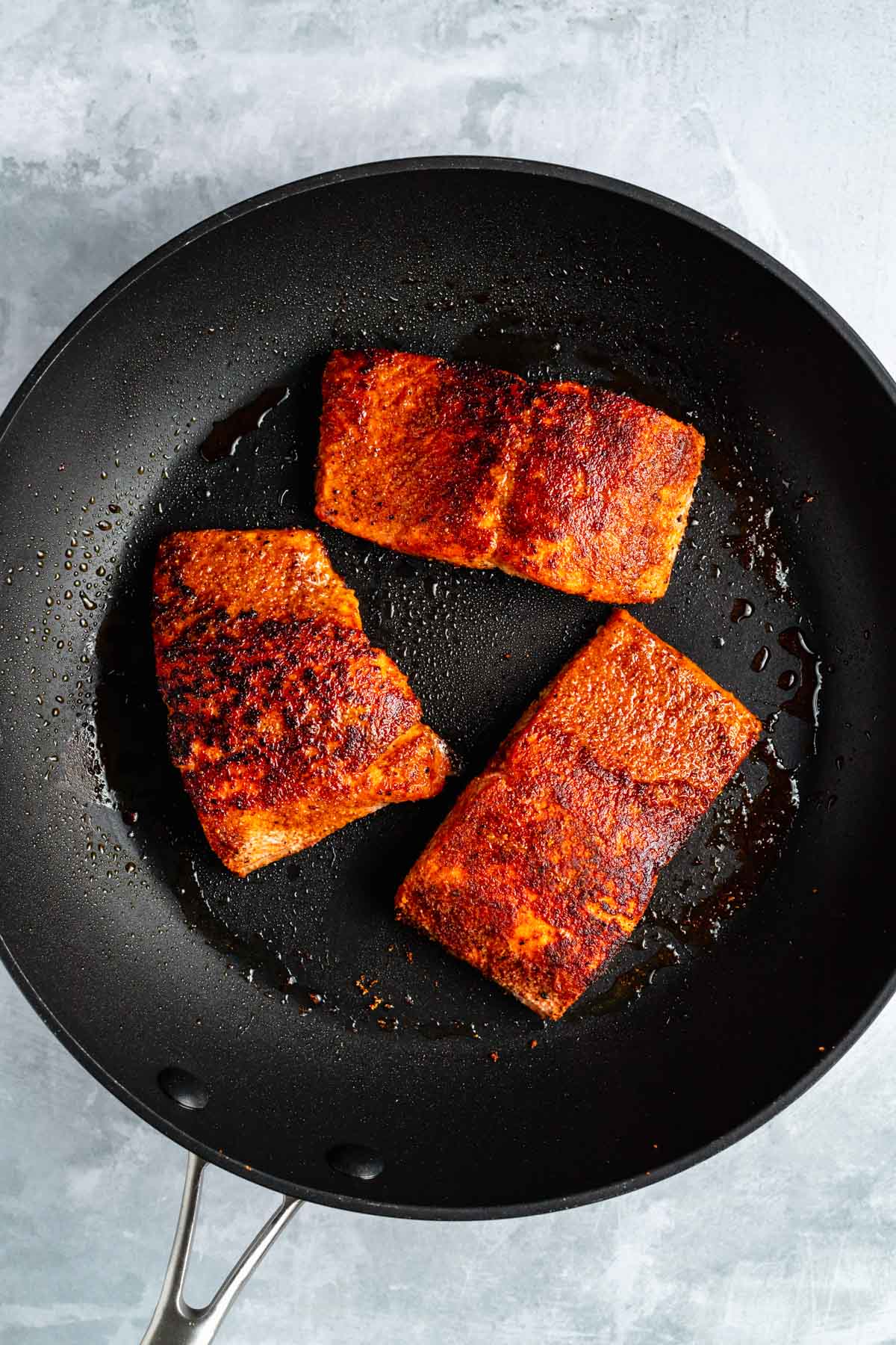 Salmon fillets cooking in a large skillet.