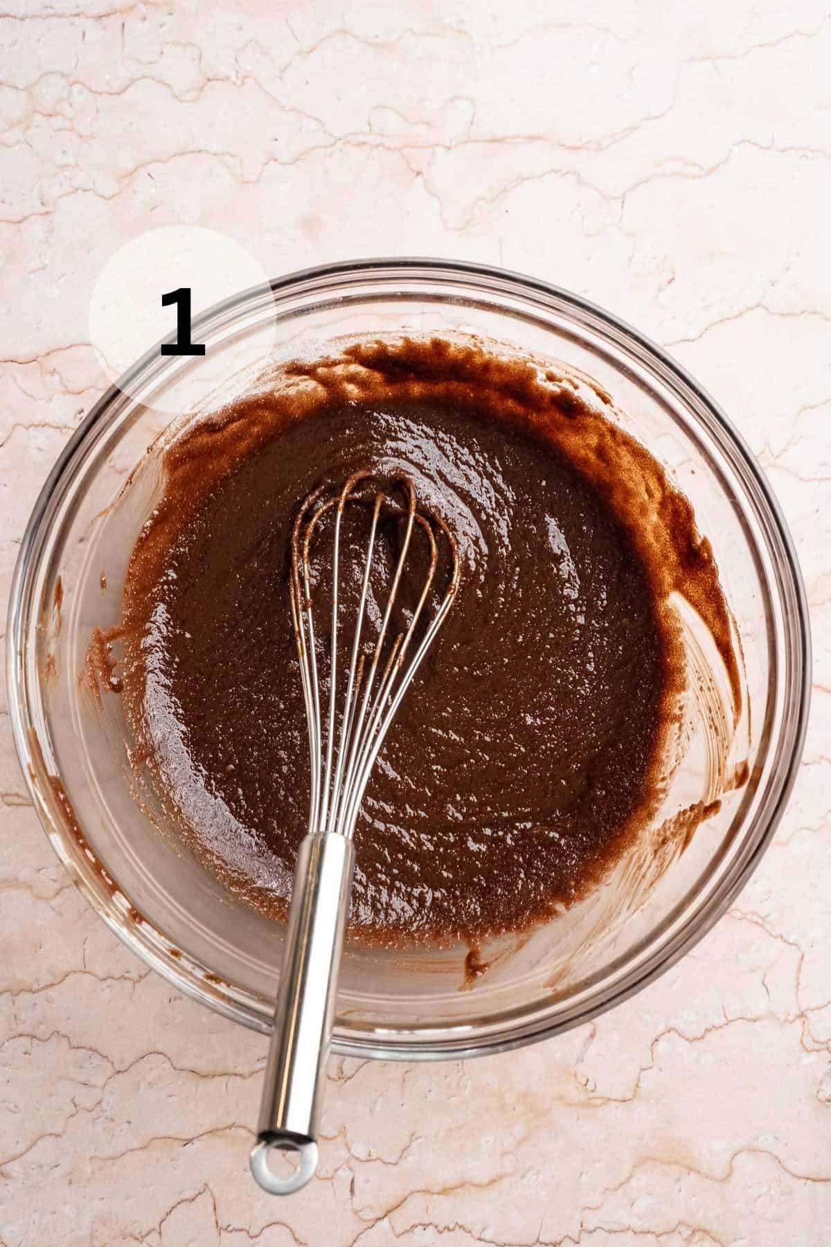 Stirring cocoa with melted chocolate and butter with a whisk.