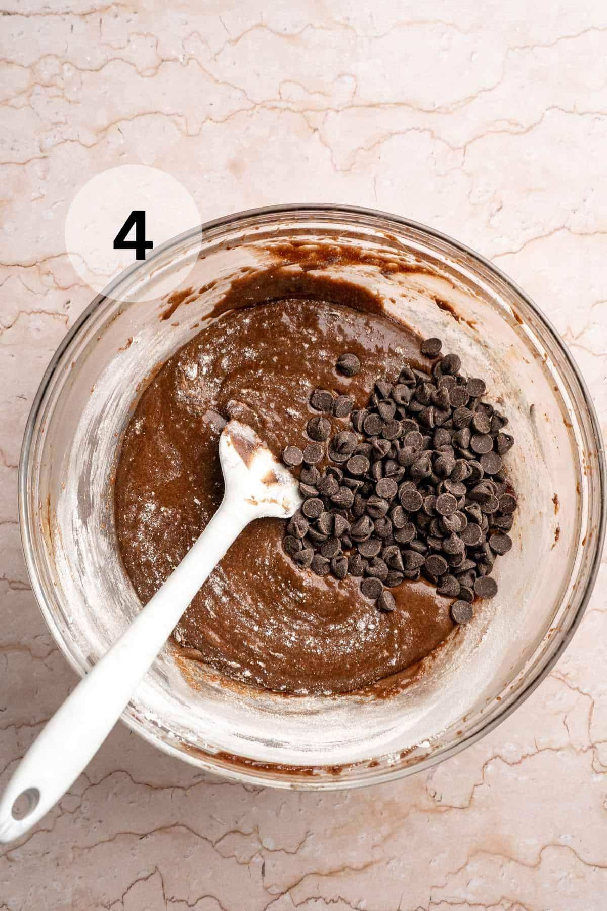 Stirring chocolate chips into brownie batter.
