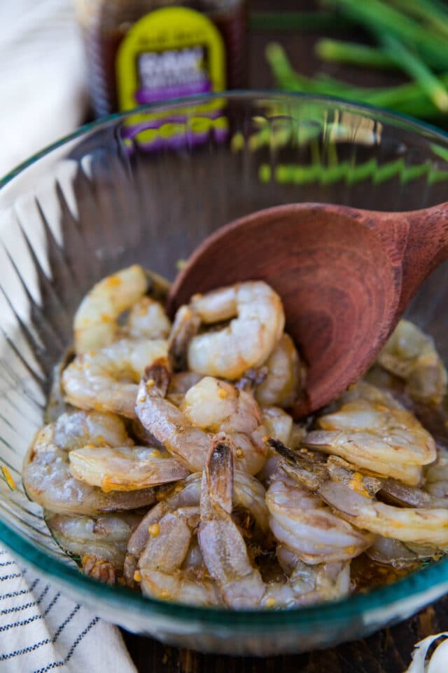 raw shrimp in a glass mixing bowl with a marinade