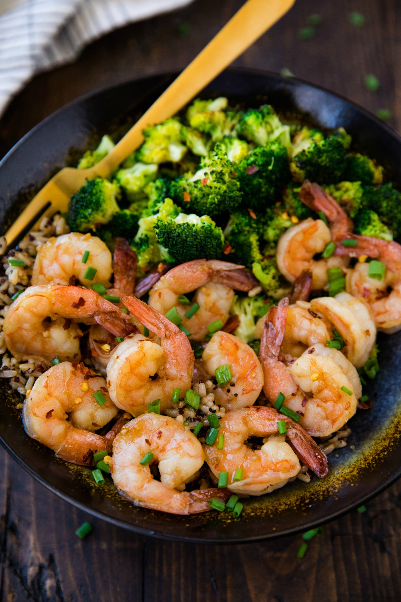 cooked shrimp in a black bowl with brown rice and broccoli