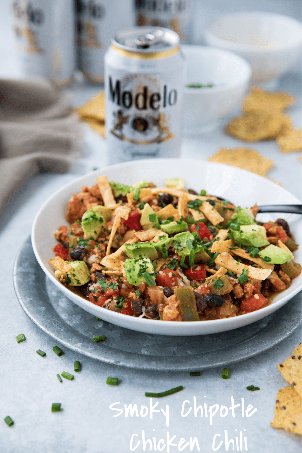 Smoky Chipotle Chicken Chili in a white bowl served with beer and tortilla chips