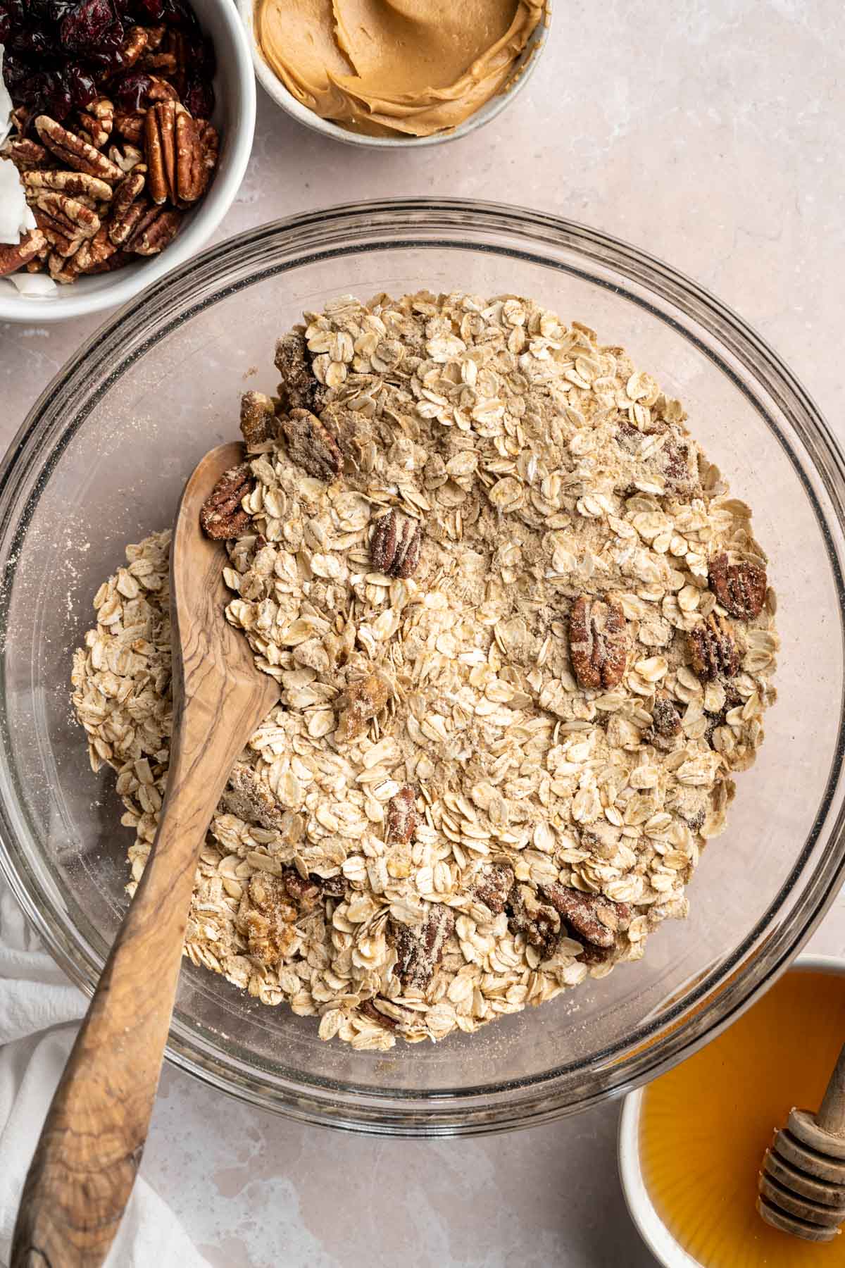 Stirring rolled oats with nuts and protein powder in a large bowl.