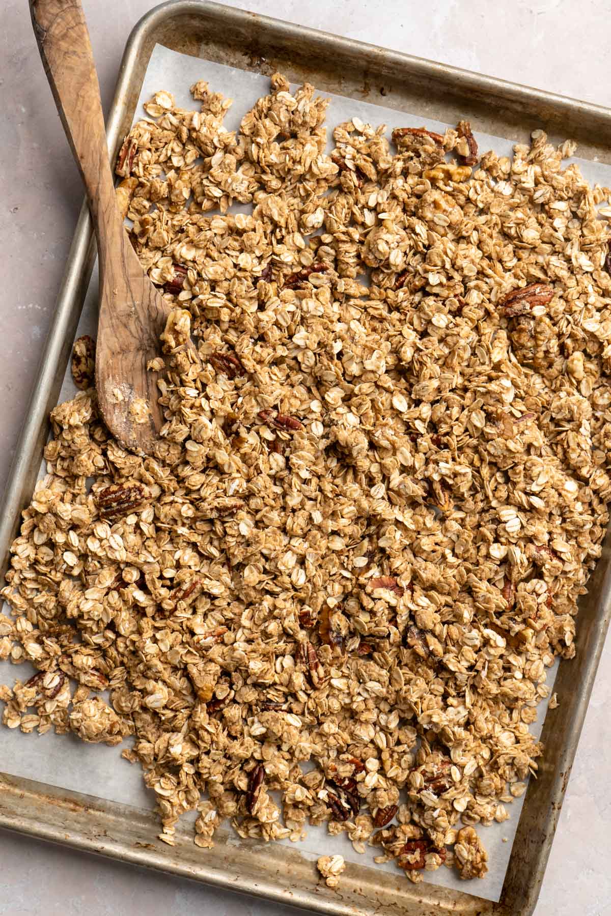 Spreading granola over a sheet pan.