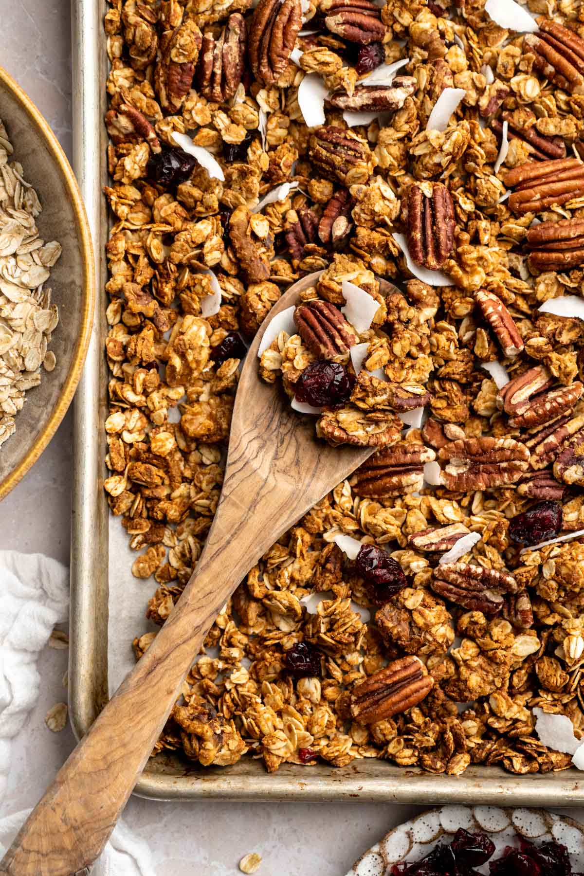 Mixing protein granola on a baking sheet with a wooden spoon.