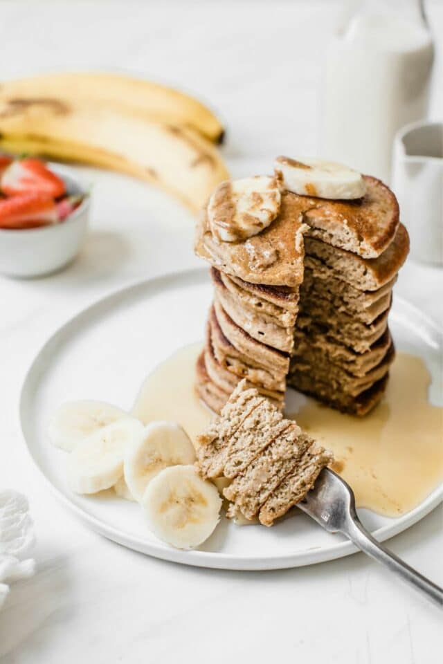 large stack of banana pancakes on a white plate