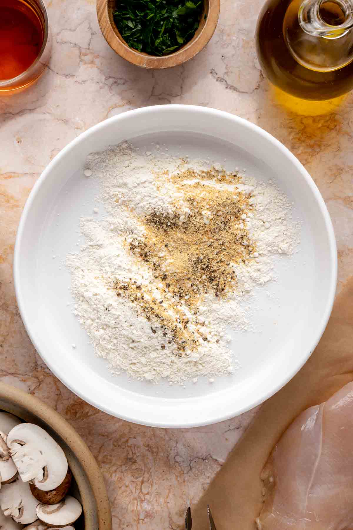 Mixing flour with seasonings in a shallow bowl.