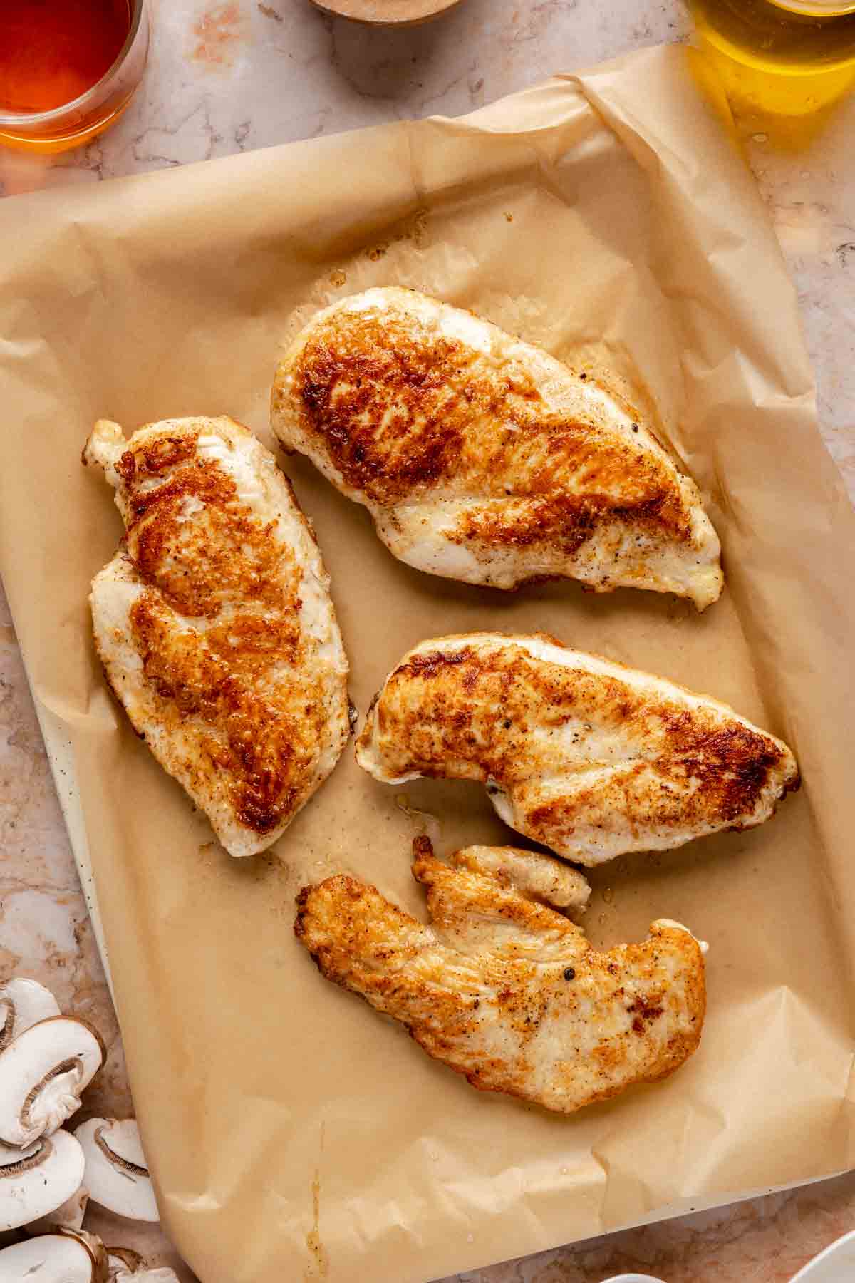 Cooked chicken breasts on parchment paper.