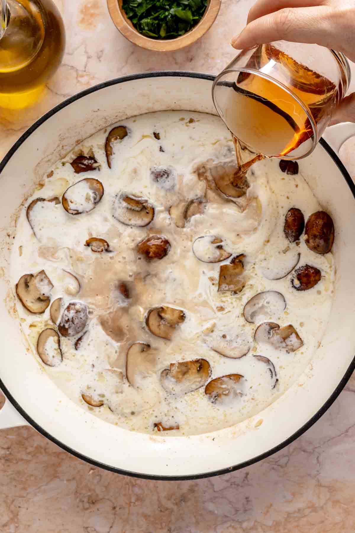 Pouring wine into the mushrooms and cream.