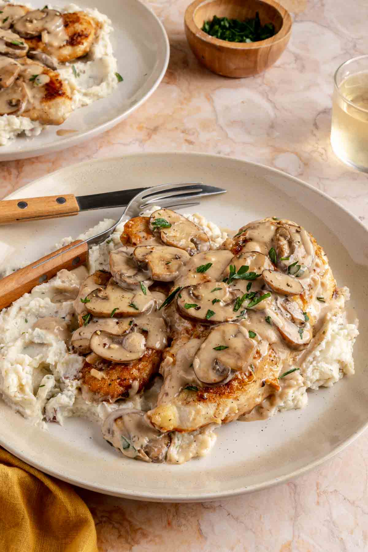Chicken breasts topped with mushrooms served with mashed potatoes.