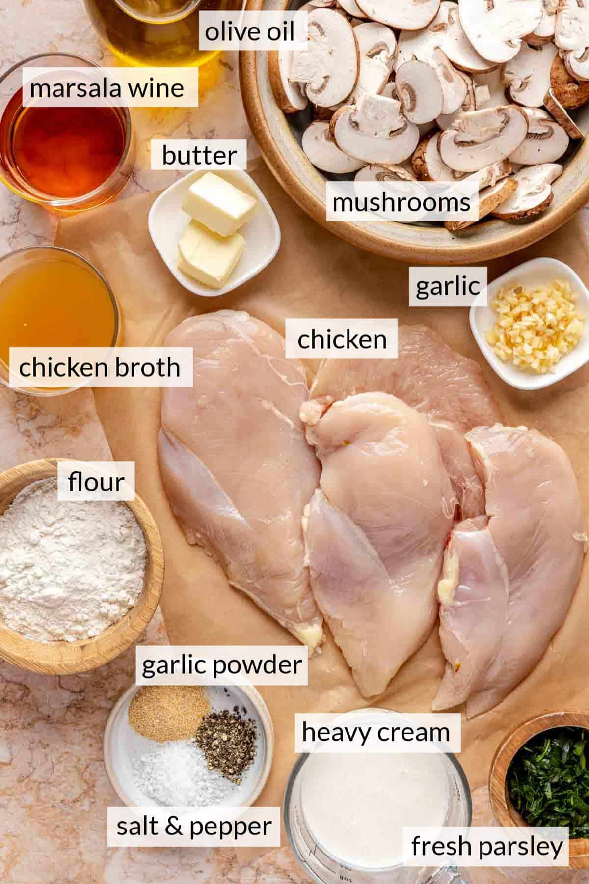 Chicken breasts near bowls of ingredients like mushrooms, garlic, butter, flour, cream and seasonings.